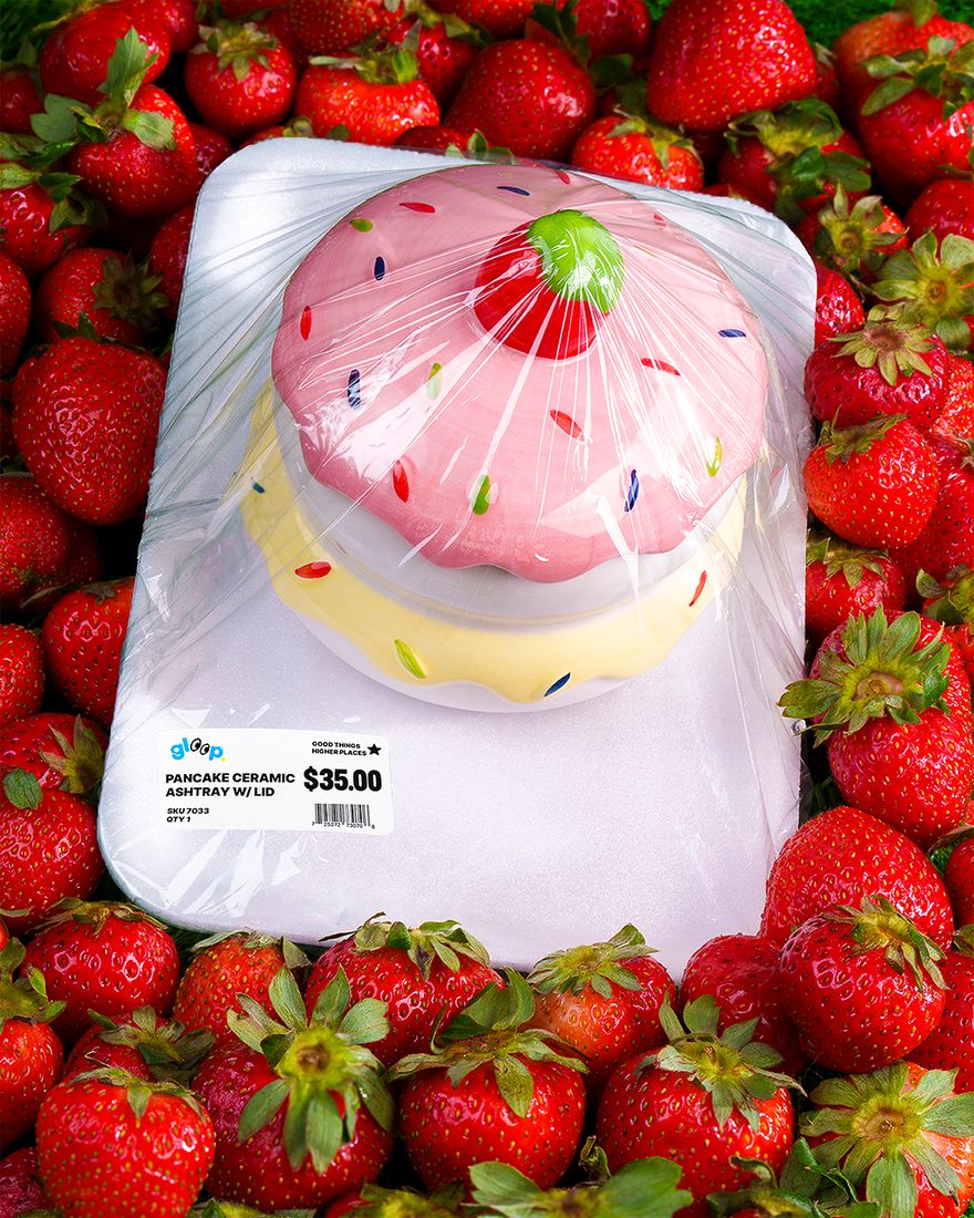 A pink glass product on white packaging surrounded by strawberries.