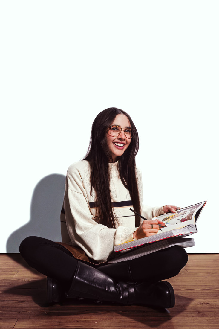 Mima sitting cross-legged on the floor with an open magazine.
