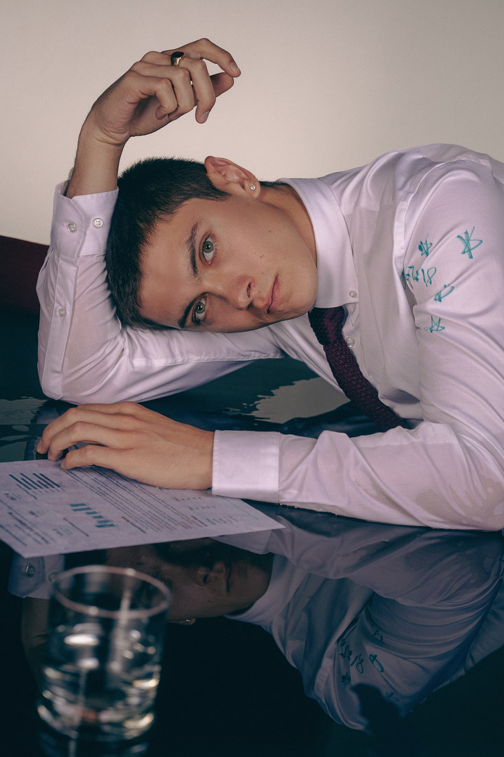 Models in shirts and ties posed around an office table.